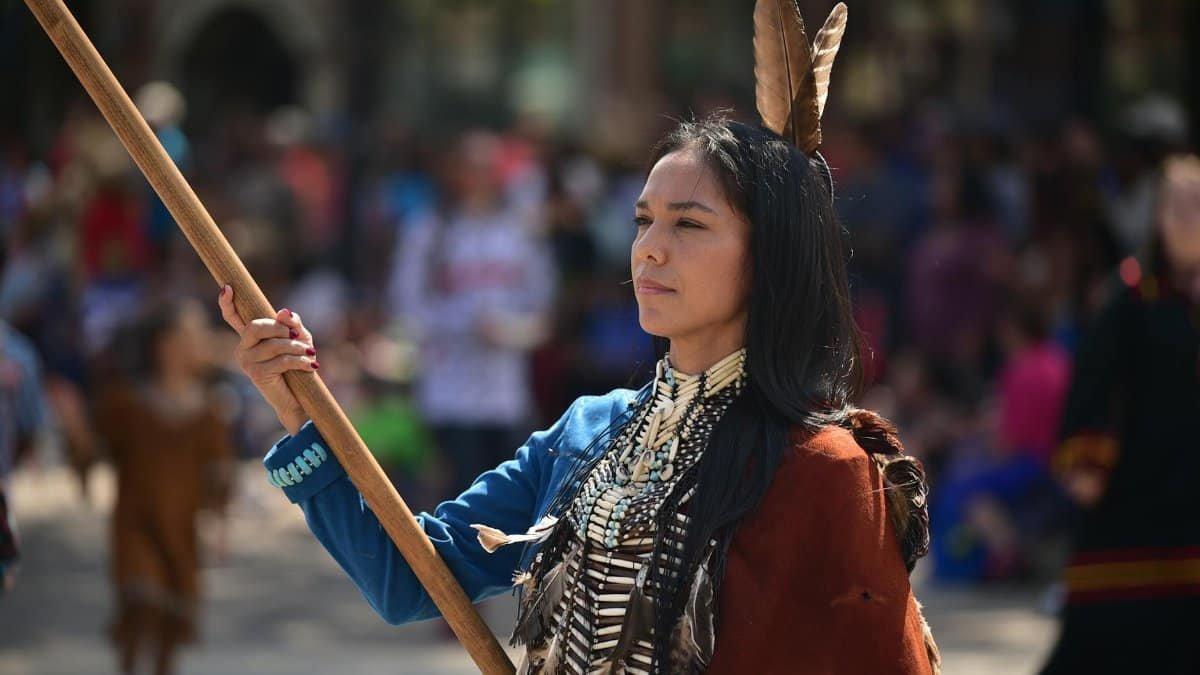 Native American woman in traditional clothing, showcasing cultural heritage at an outdoor event.