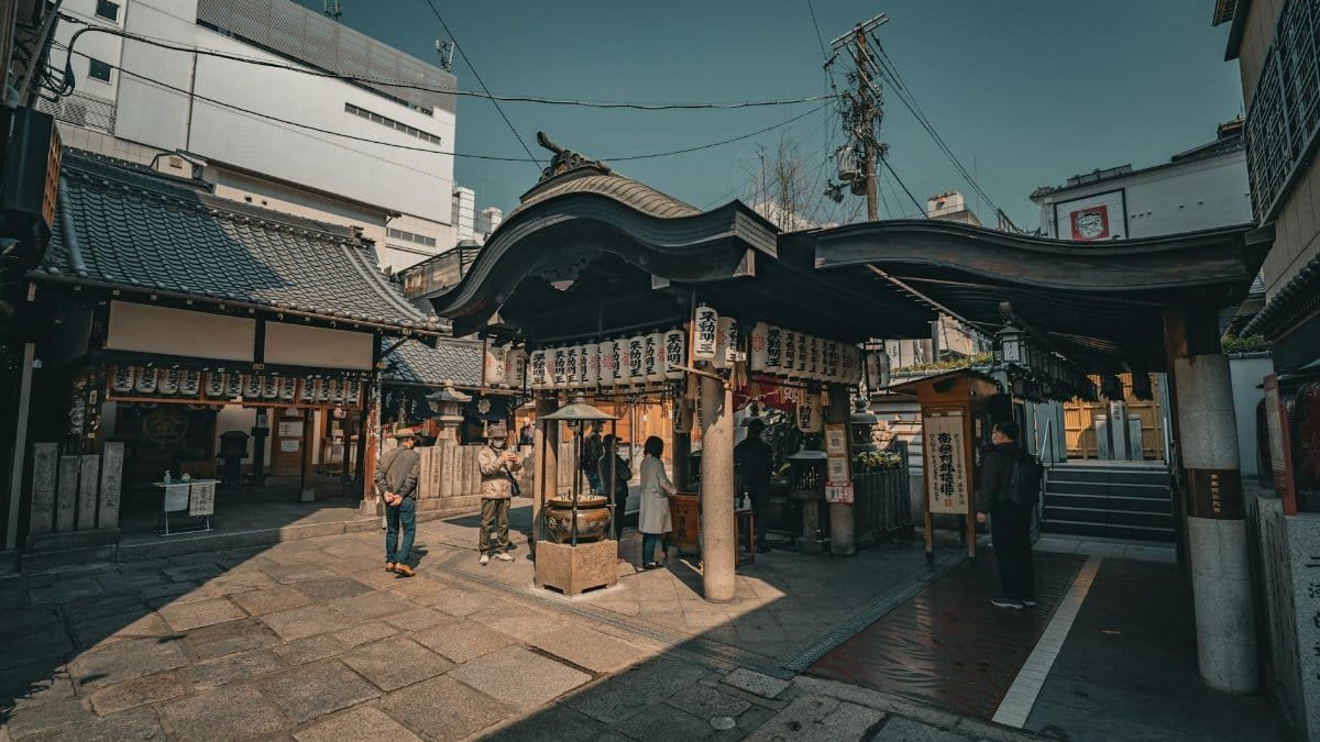 People visiting a historic temple in Osaka, showcasing traditional architecture and cultural practices.