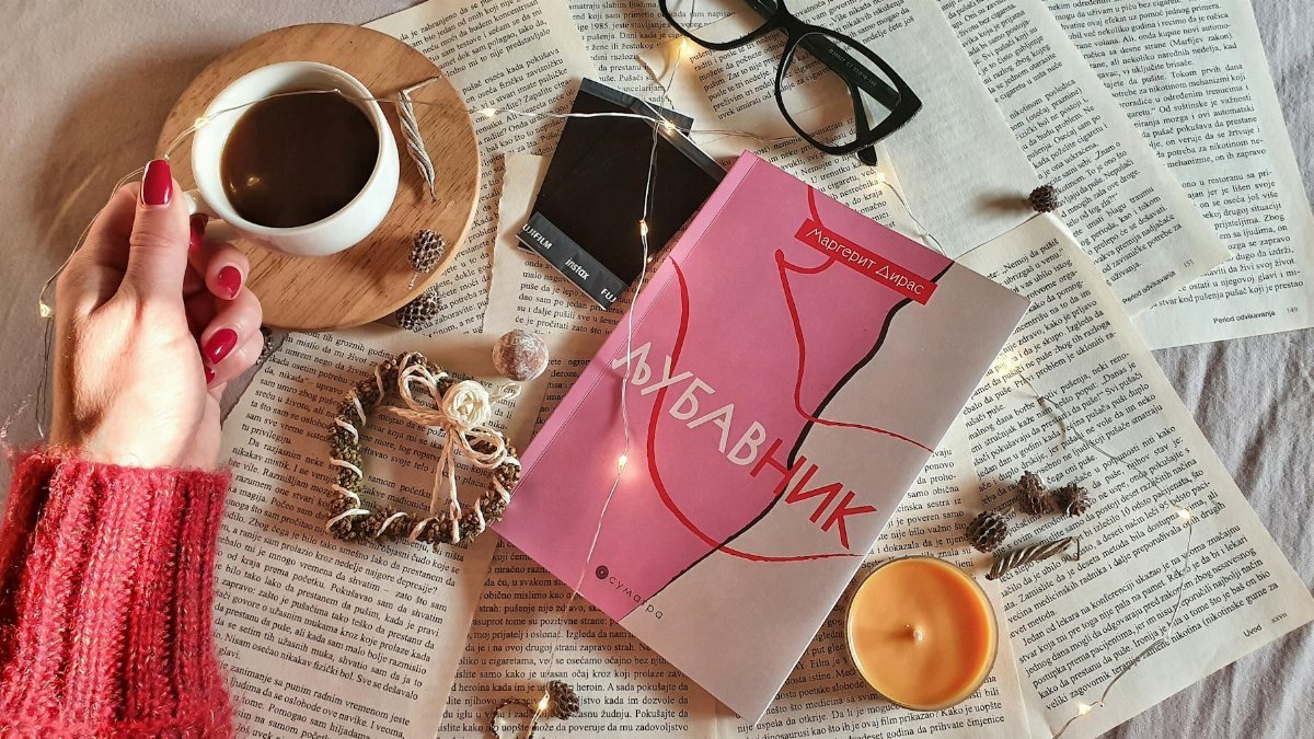 A cozy setup of coffee, book, and string lights for a relaxing reading experience.