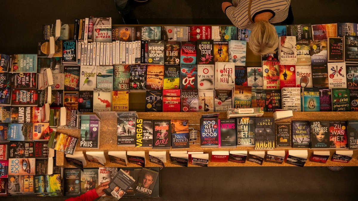 Overhead shot of a bookstore table filled with various books, with a customer browsing.