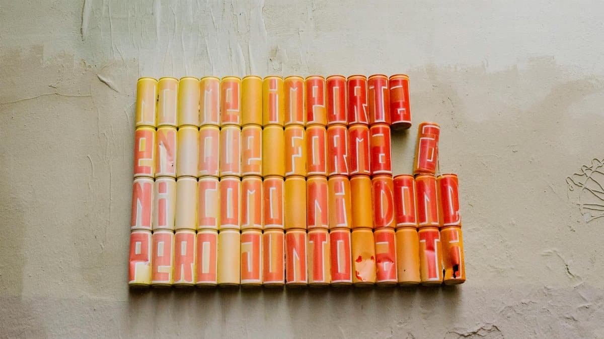 Creative art installation with colored soda cans forming text on a wall.