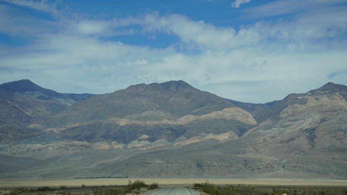 Vast mountain landscape in Death Valley National Park with a deserted road stretching into the distance.