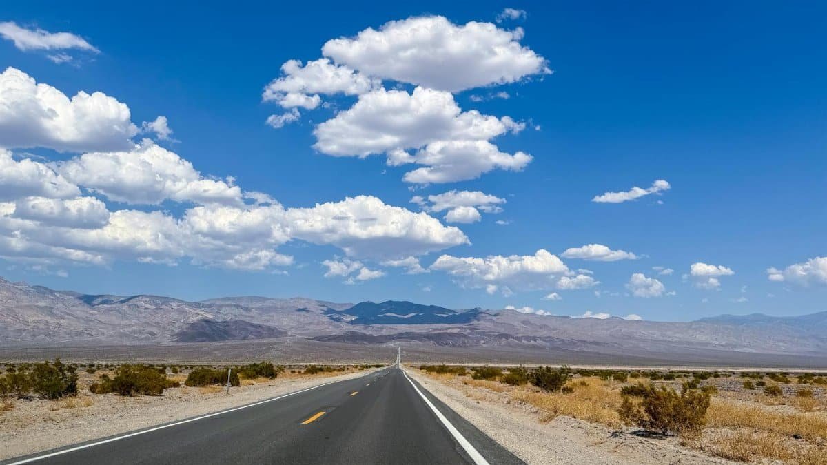 Captivating view of an endless road in Death Valley with blue skies and mountains.
