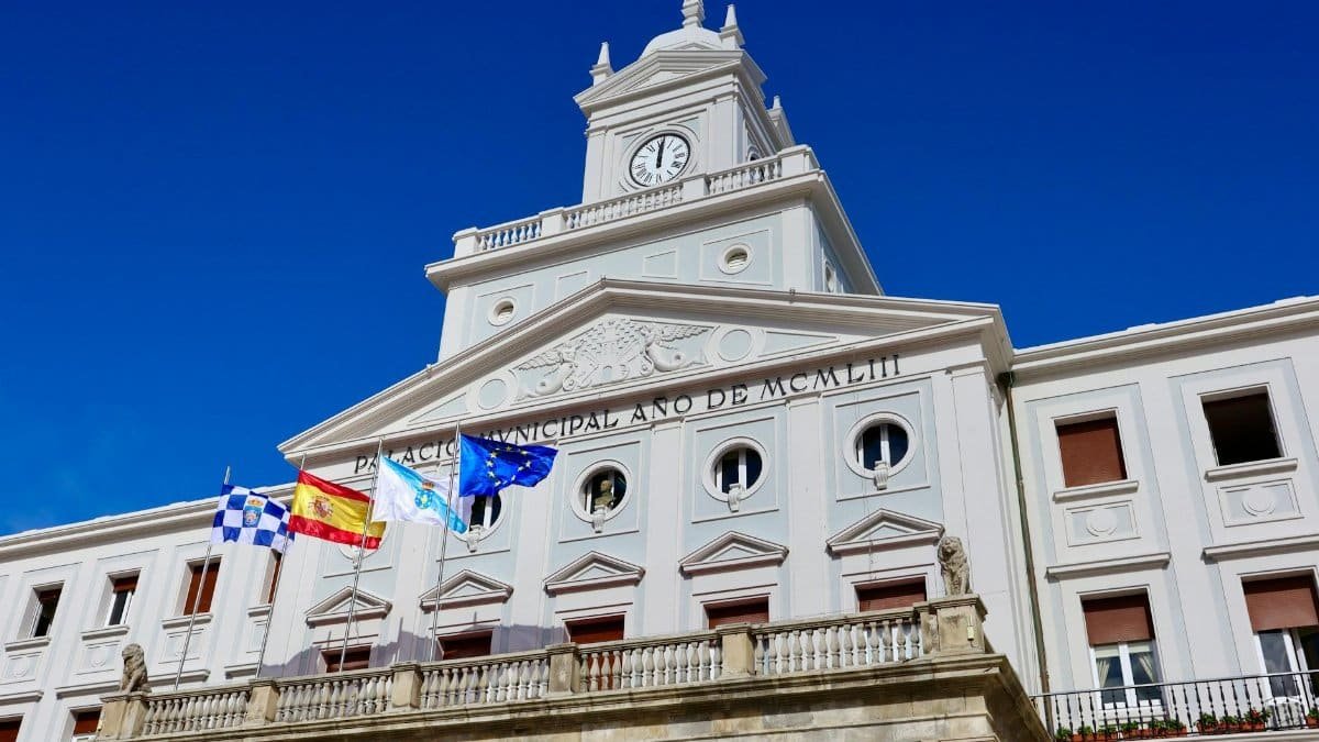 Low-angle view of the Municipal Palace with flags in Ferrol, Spain on a sunny day.