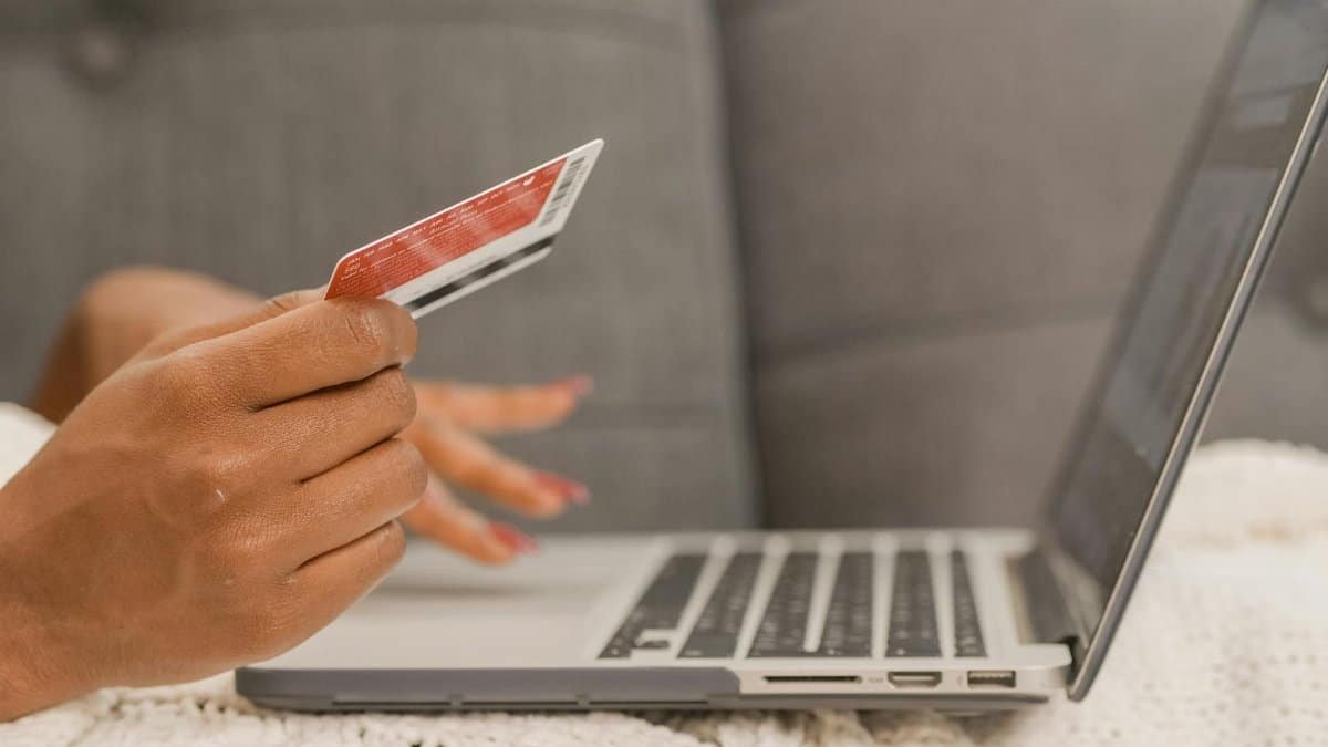 Close-up of a person using a credit card for online shopping on a laptop.