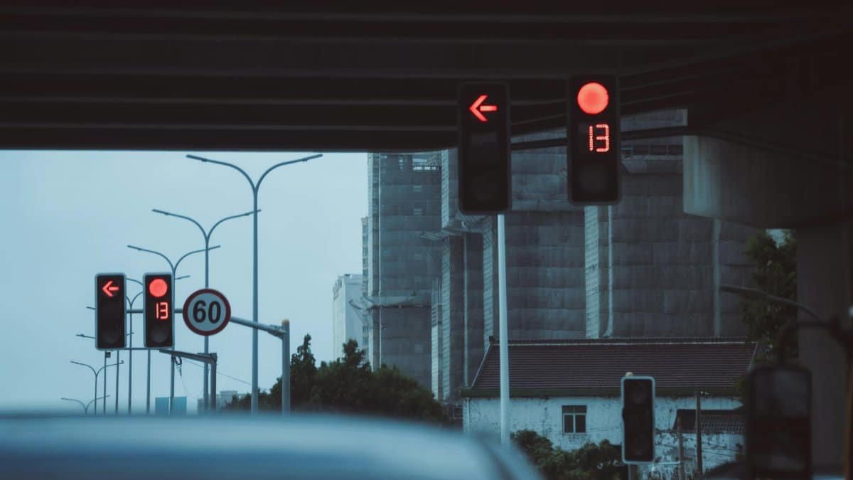 Moody urban street scene with red traffic lights and countdown timer under a bridge.