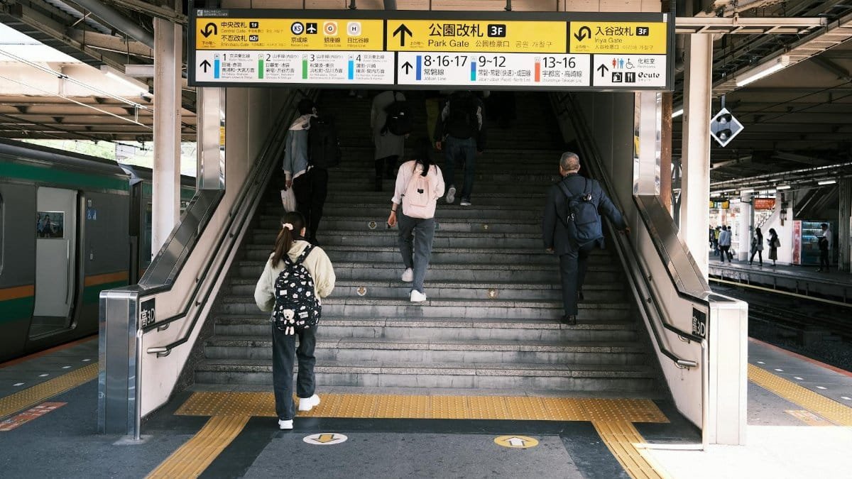 People ascending stairs at a Tokyo railway station, emphasizing city life and public transportation.