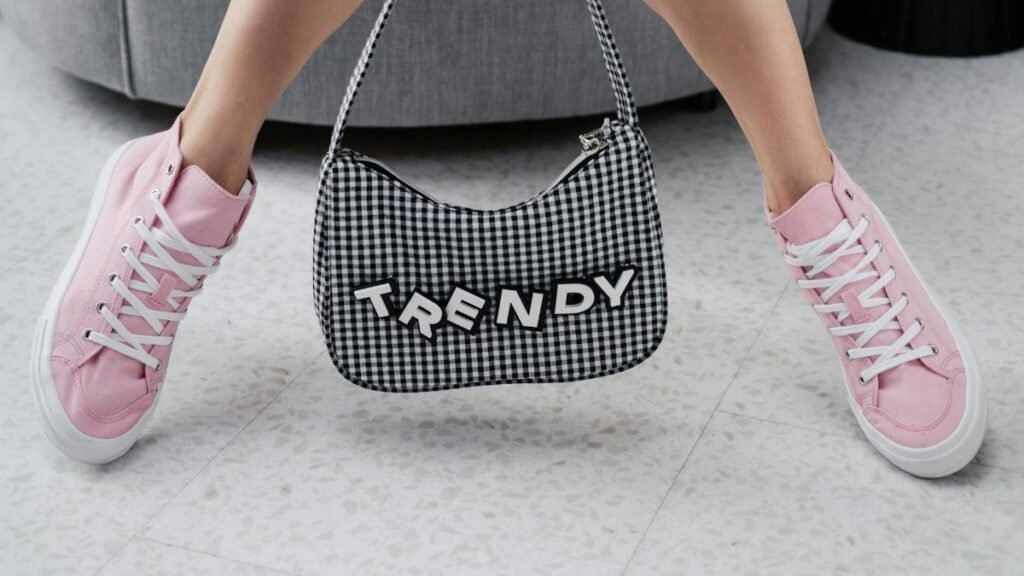 Pink sneakers paired with a trendy checked bag indoors, showcasing youthful fashion.