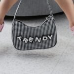 Pink sneakers paired with a trendy checked bag indoors, showcasing youthful fashion.