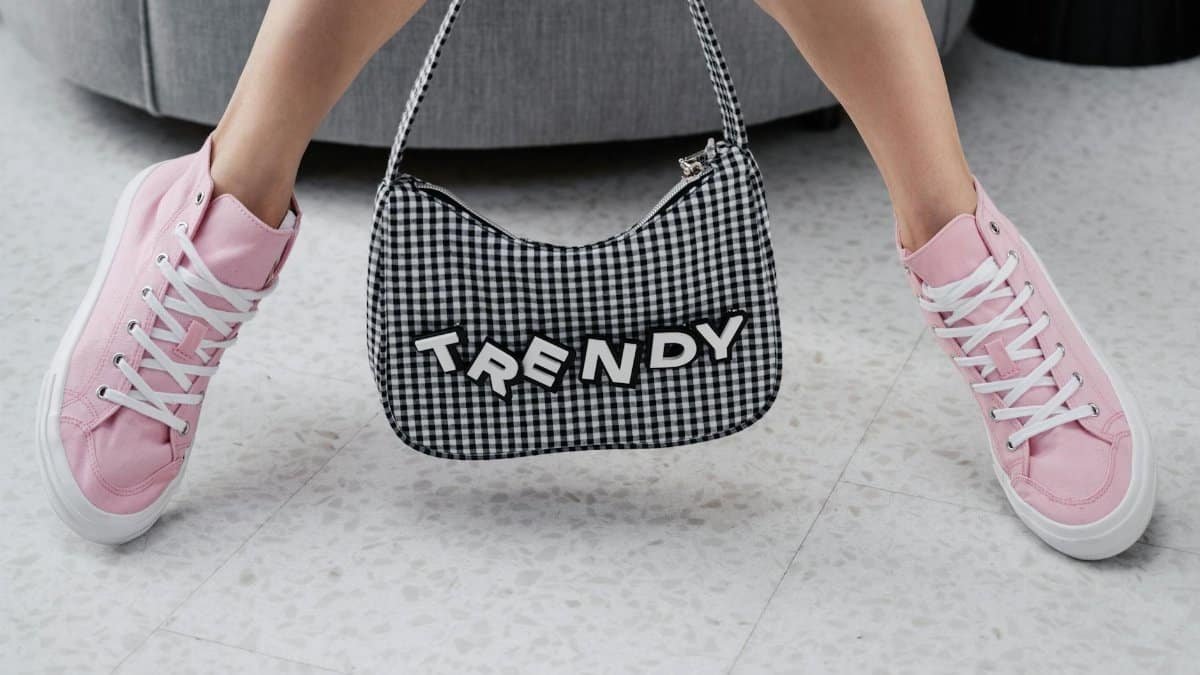 Pink sneakers paired with a trendy checked bag indoors, showcasing youthful fashion.