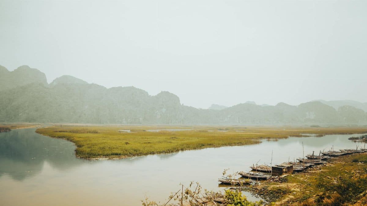 Serene landscape of a peaceful river surrounded by lush green mountains in Vietnam.