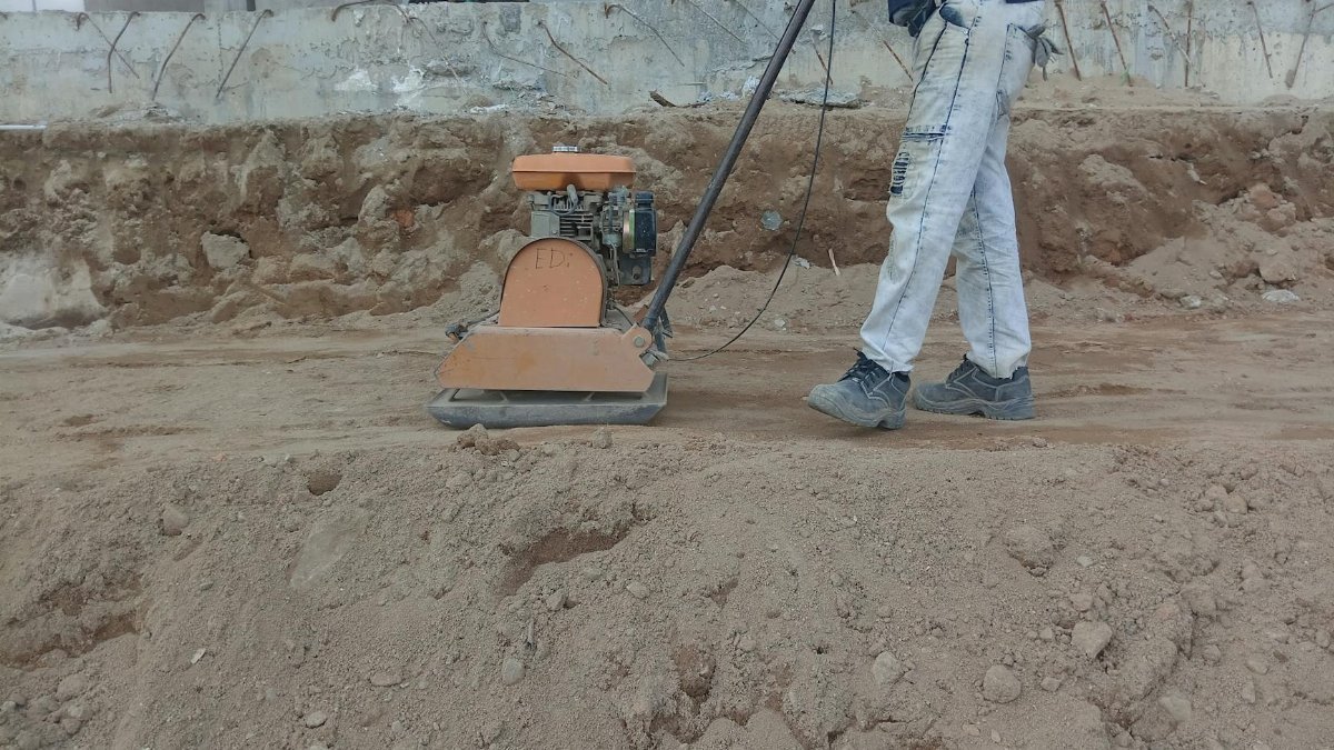 A construction worker using a soil compactor outdoors for groundwork.