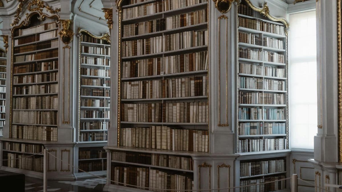 An opulent library featuring classical architecture and ornate woodwork with a vast collection of decorative books.