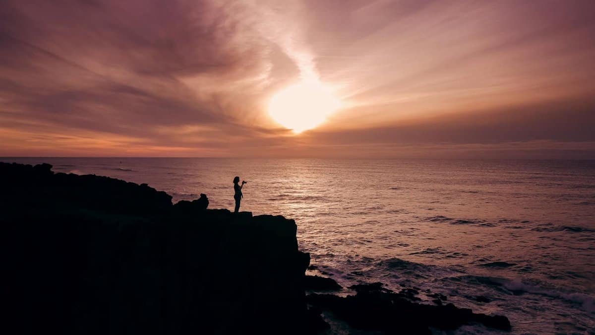 Silhouette of a woman on a cliff during a breathtaking sunset at Depoe Bay, Oregon.