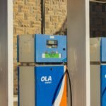 Three blue OLA Energy gas pumps at an outdoor station on a sunny day.