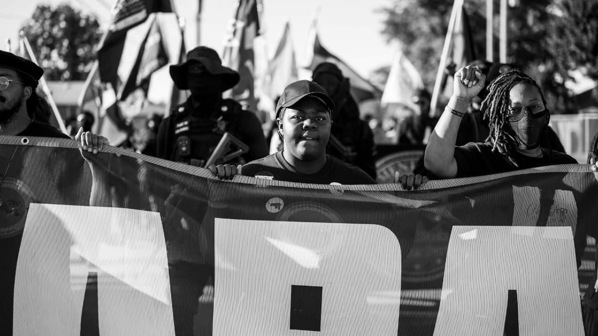A powerful black and white image of protestors holding a banner during a demonstration in Tulsa, Oklahoma.