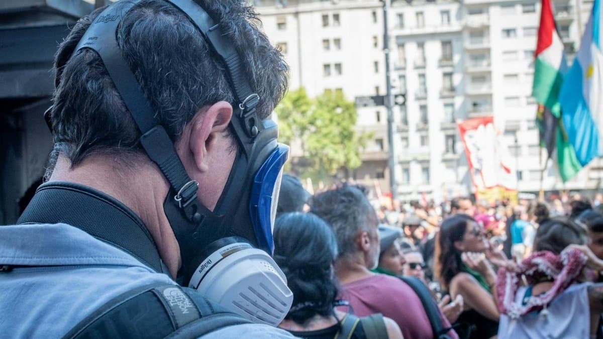 Man wears protective mask amidst crowd during protest in Buenos Aires.