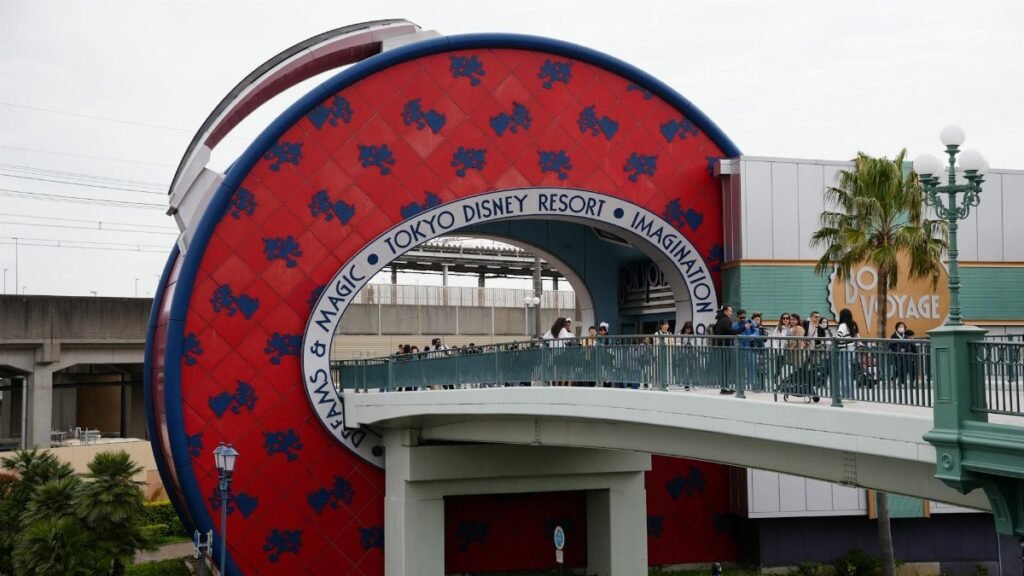 Capture of the Tokyo Disney Resort entrance featuring the Bon Voyage Store and pedestrian bridge.