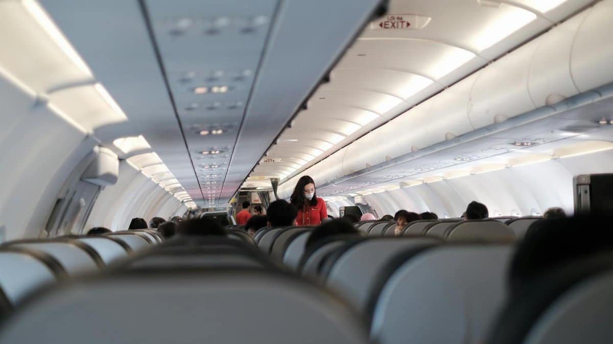 Passengers and flight attendant inside a Vietnam commercial aircraft. Travel safety with masks.