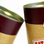 Close-up view of warning labels on canned food containers indicating caution and safety.