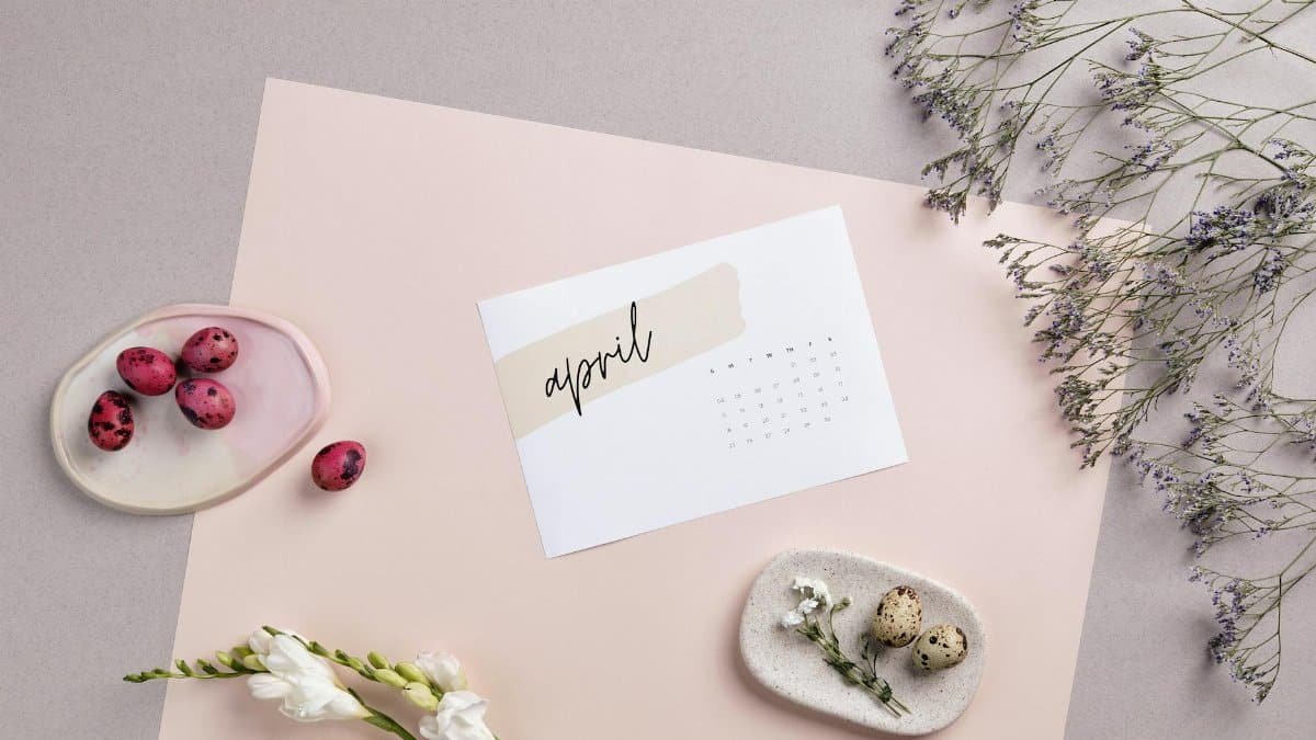 Flat lay of April calendar with florals, painted eggs, and pastel colors for Easter decoration.