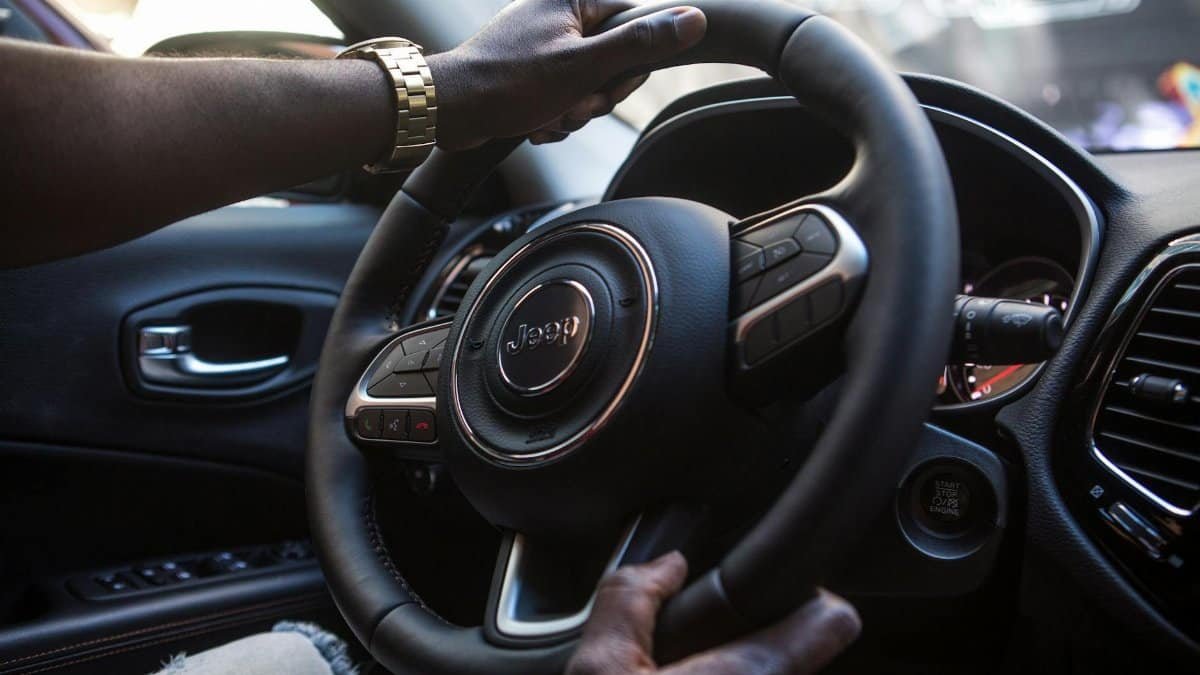 Close-up of a man's hands on a luxury car steering wheel highlighting modern interior.