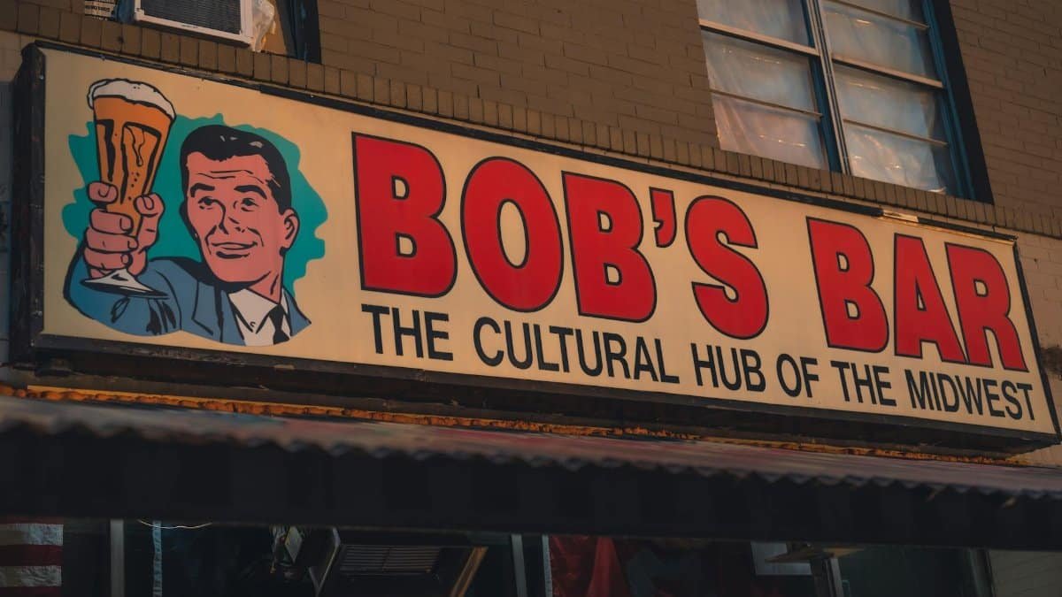 Vintage bar sign reading 'Bob's Bar: The Cultural Hub of the Midwest' with a retro illustration.