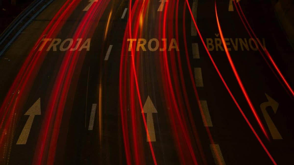 Long-exposure shot of urban highway with light trails and directional arrows, creating a dynamic night scene.