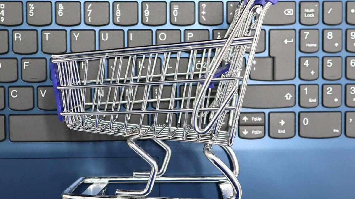 A miniature shopping cart placed on a laptop keyboard symbolizing online shopping and e-commerce.