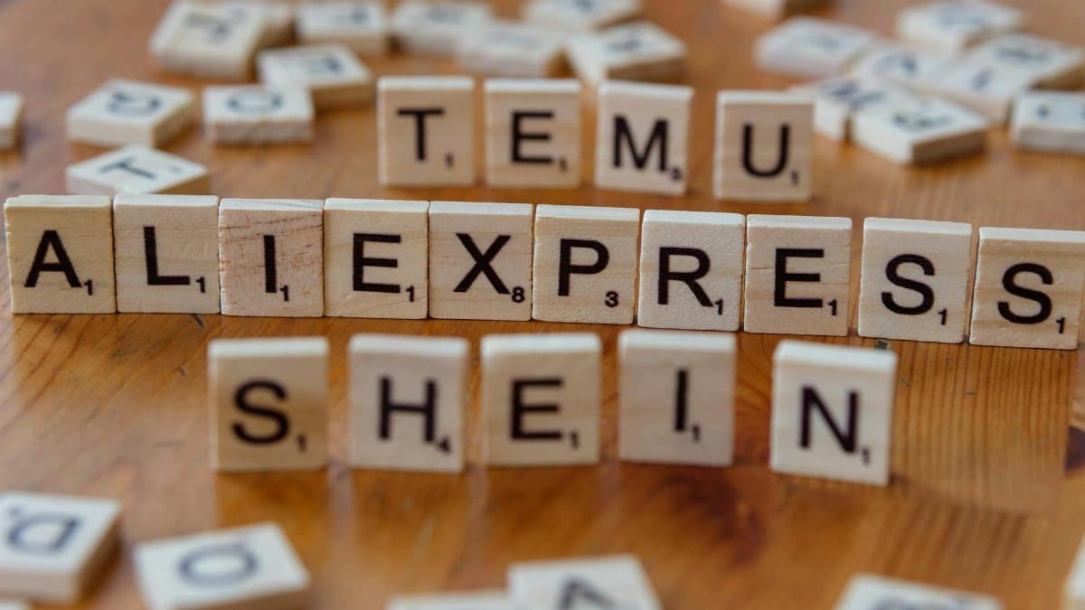 Wooden Scrabble tiles display popular e-commerce platforms on a wooden surface.