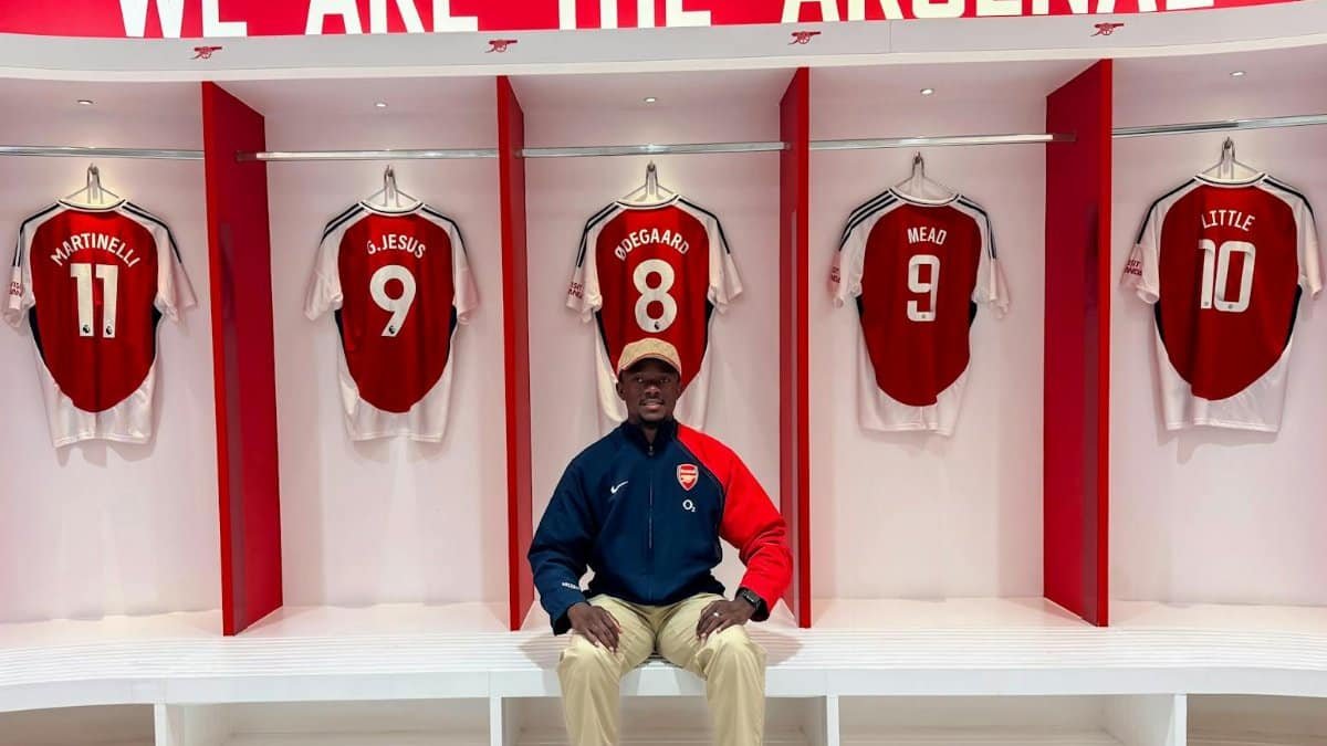 Visitor in Arsenal locker room with team jerseys and club branding.