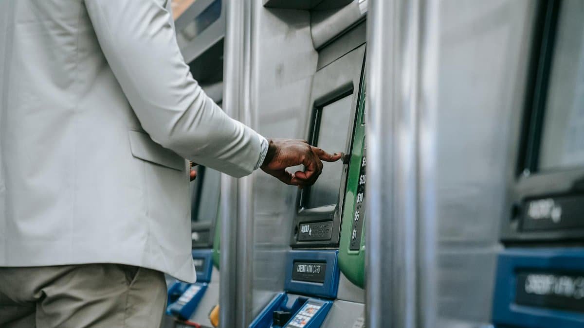 Side view of an adult using a self-service ticket machine indoors.
