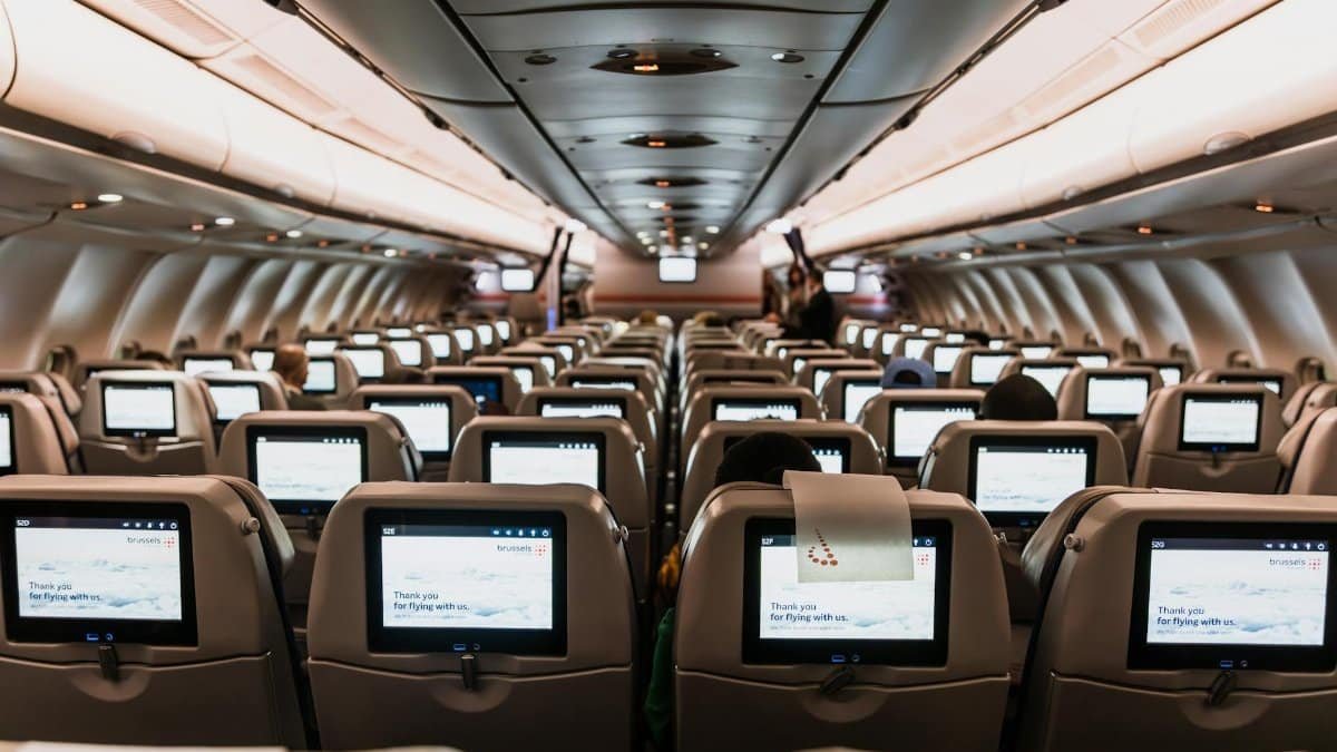 Comfortable airplane cabin interior featuring in-flight entertainment screens on all seats.