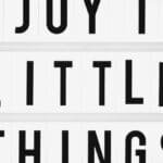 Minimalist design of the inspirational quote 'Enjoy The Little Things' displayed on a lightbox.