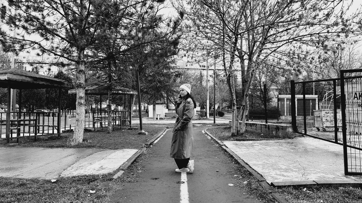 Black and white photo of a woman in a park on a winter day, creating a moody atmosphere.