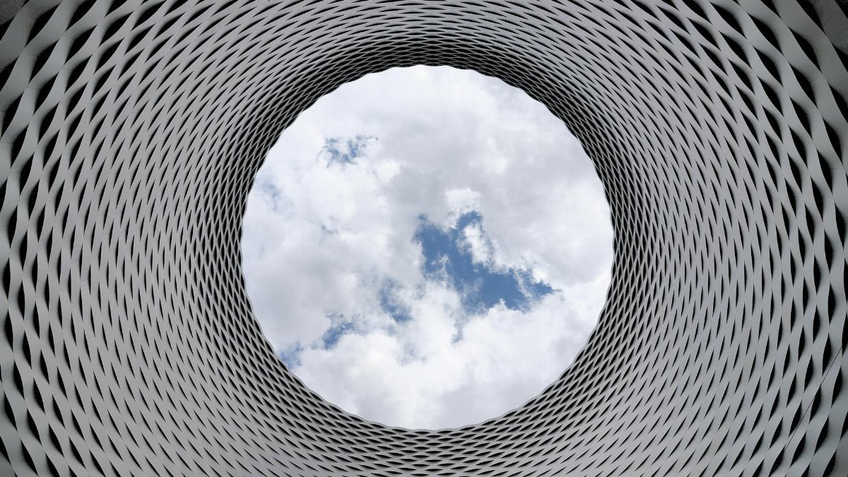 Modern architectural tunnel with a geometric pattern revealing a bright sky.