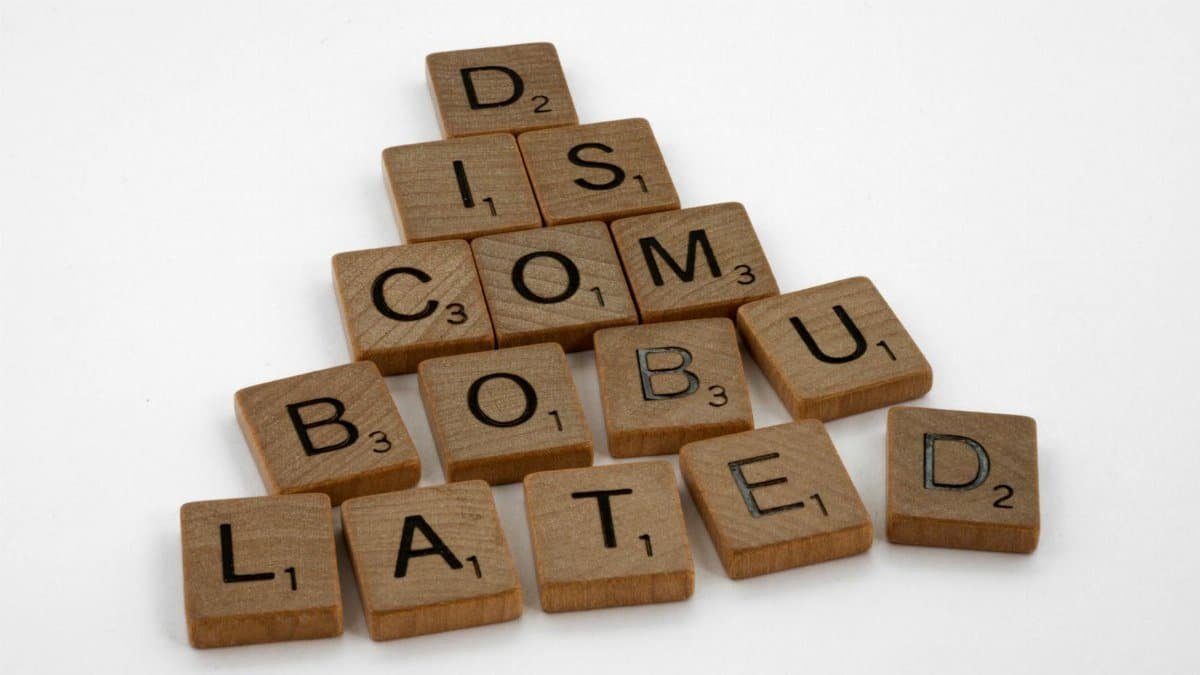 Scrabble tiles arranged to spell 'discombobulated' on a clean white surface, ideal for concept art.