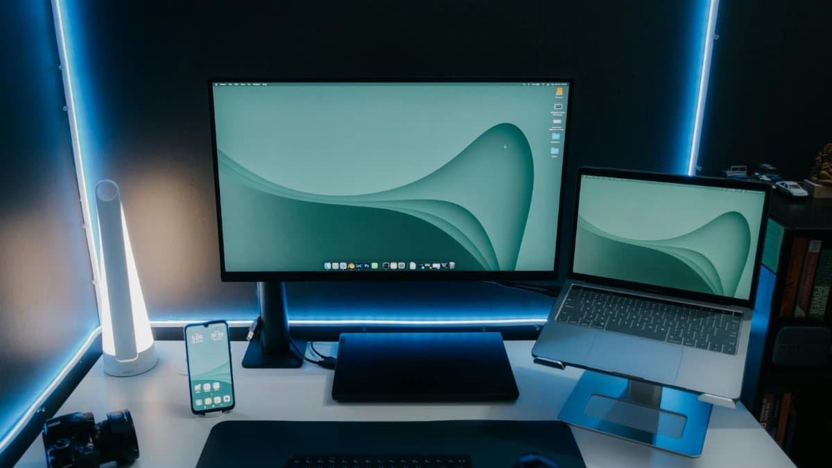 A sleek and modern desk setup featuring a monitor, laptop, and ambient lighting, perfect for productivity.
