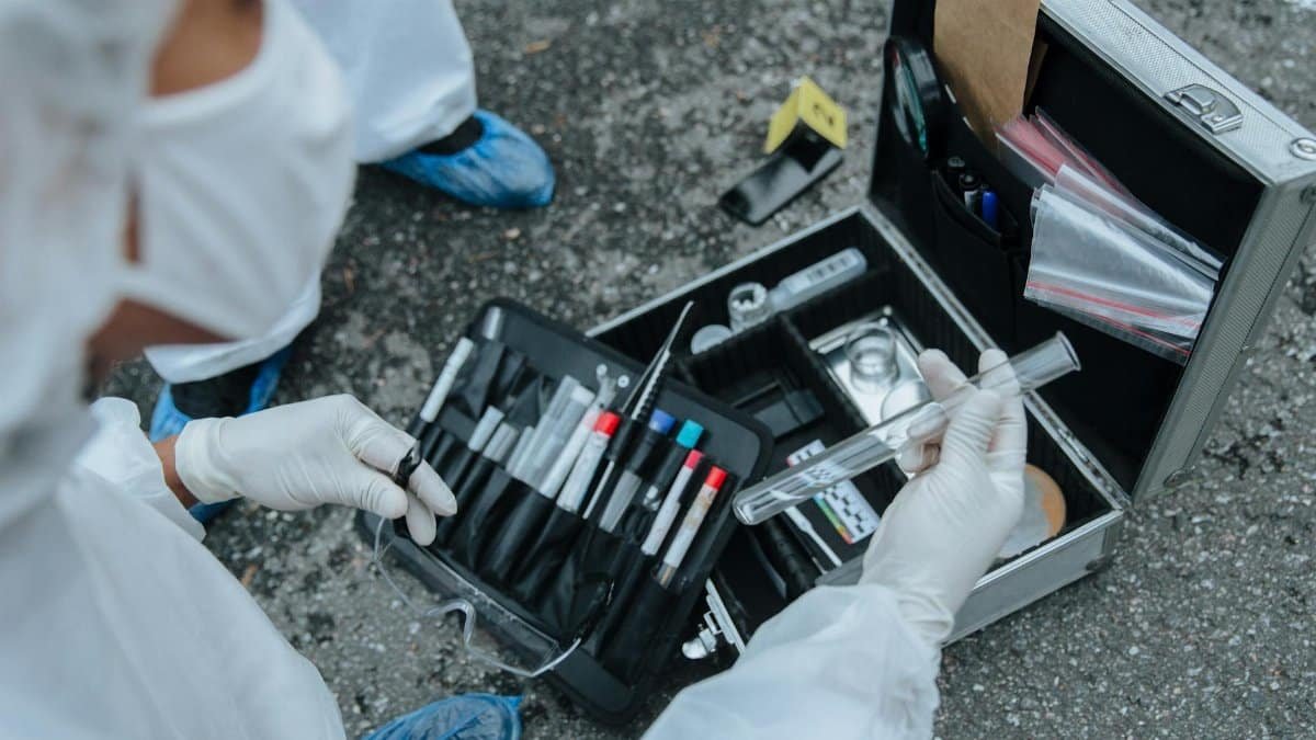 Forensic expert examining evidence with tools at a crime scene investigation outdoors.