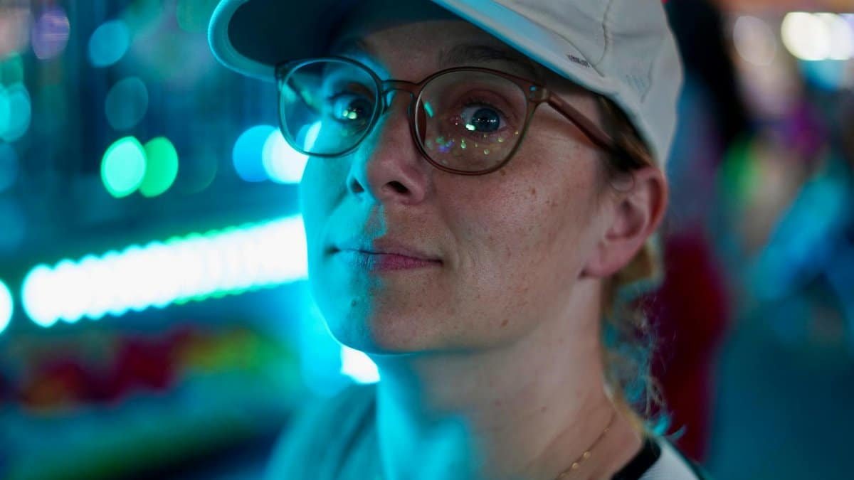 A thoughtful person at a vibrant night fair in Tampa, FL with colorful bokeh.