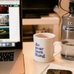 Cozy workspace with laptop, motivational mug, and water bottle, perfect for remote work inspiration.