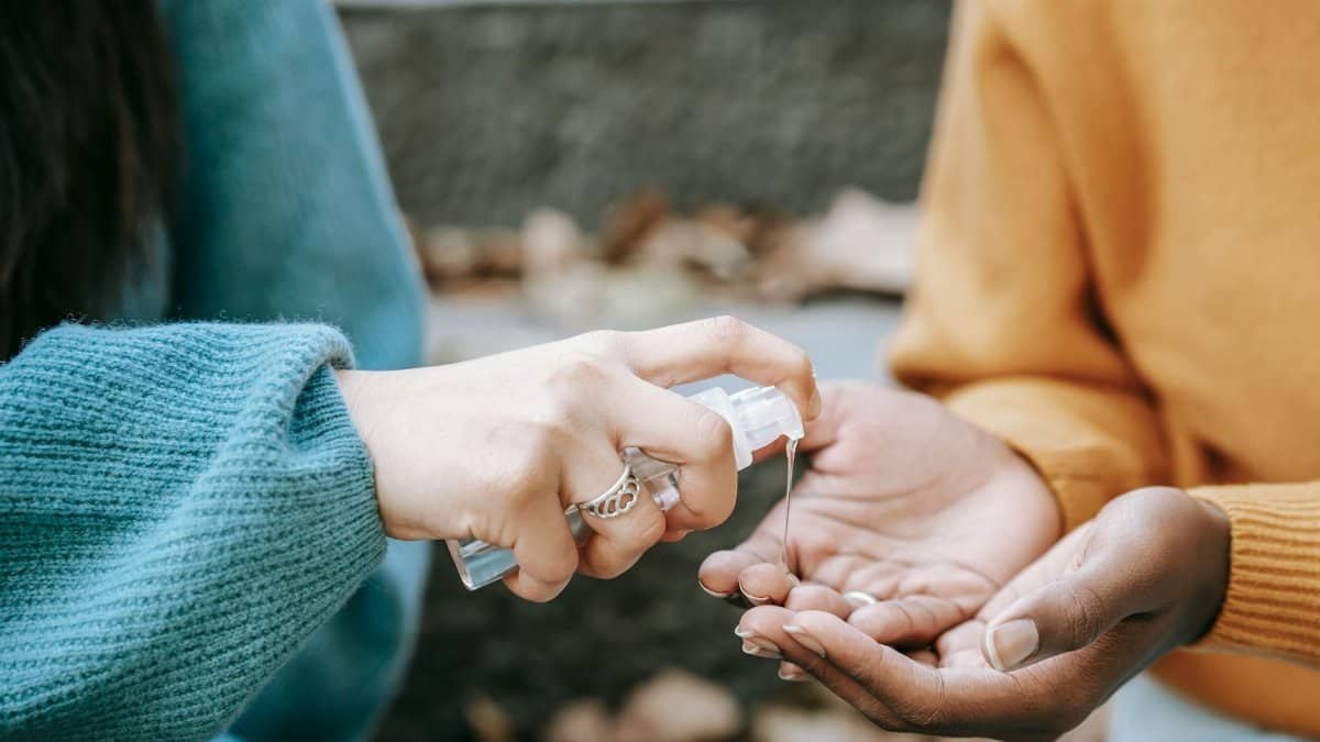 Close-up of hands using sanitizer outside during fall, promoting hygiene.