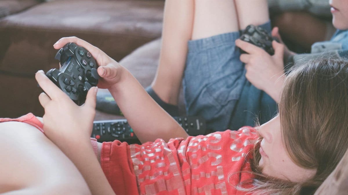 Kids lounging on the couch, focused on playing video games with controllers in hand.