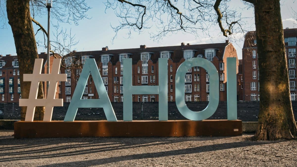 Large '#AHOI' sign with residential buildings in Bremen, Germany.