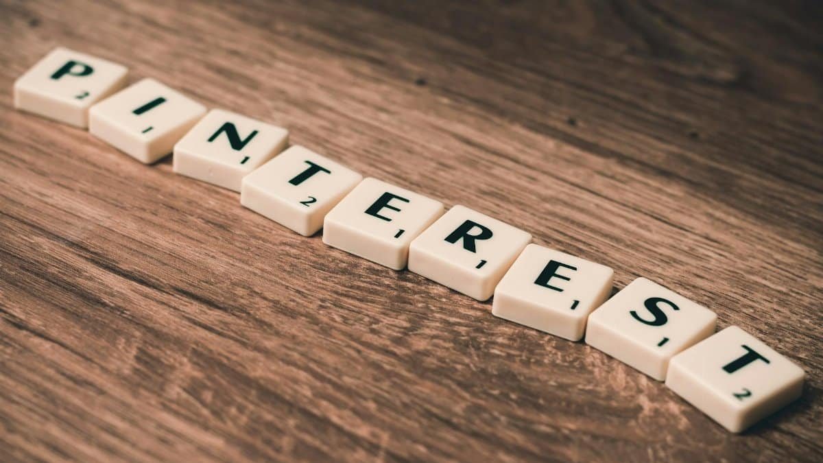 Wooden letter tiles arranged to spell Pinterest on a wooden table, ideal for social media themes.