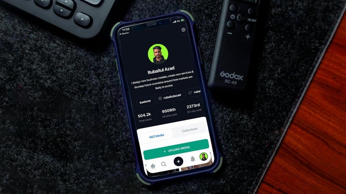 Smartphone on desk showing social media profile page with keyboard and remote nearby.