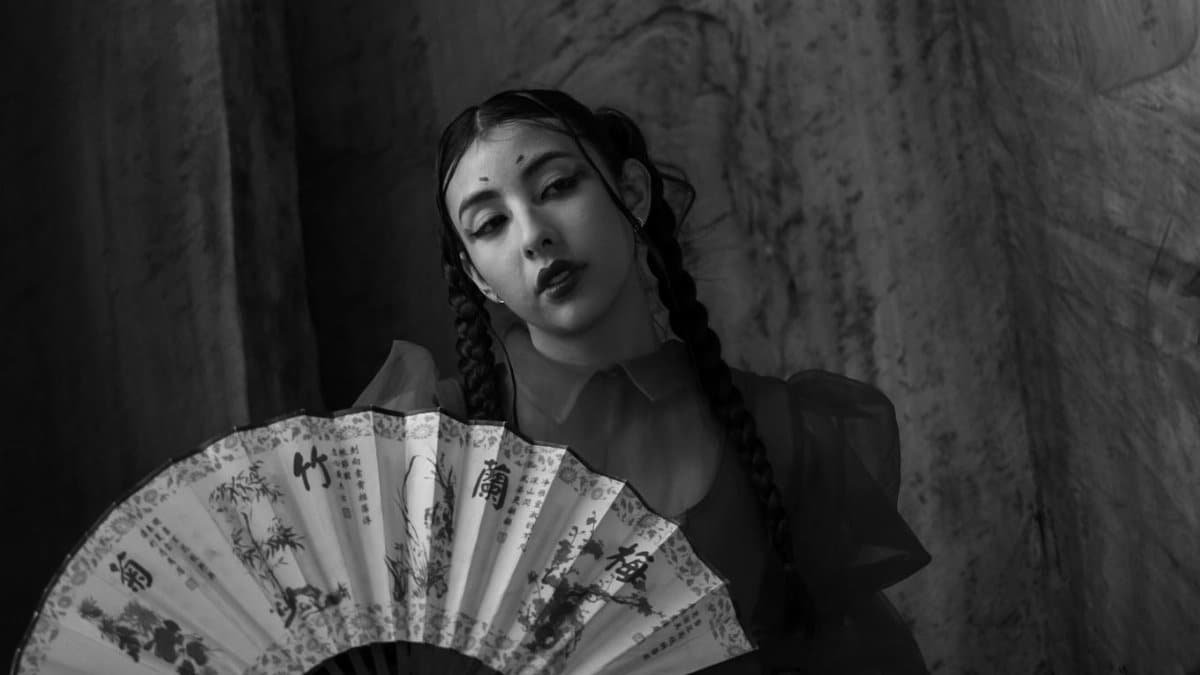 Elegant black and white portrait of a woman holding a traditional fan.
