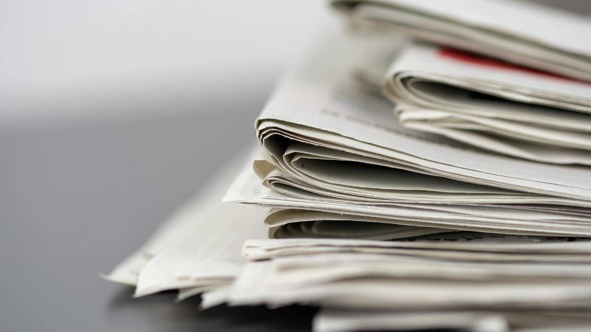 Close-up of stacked newspapers on a table, representing media and journalism.