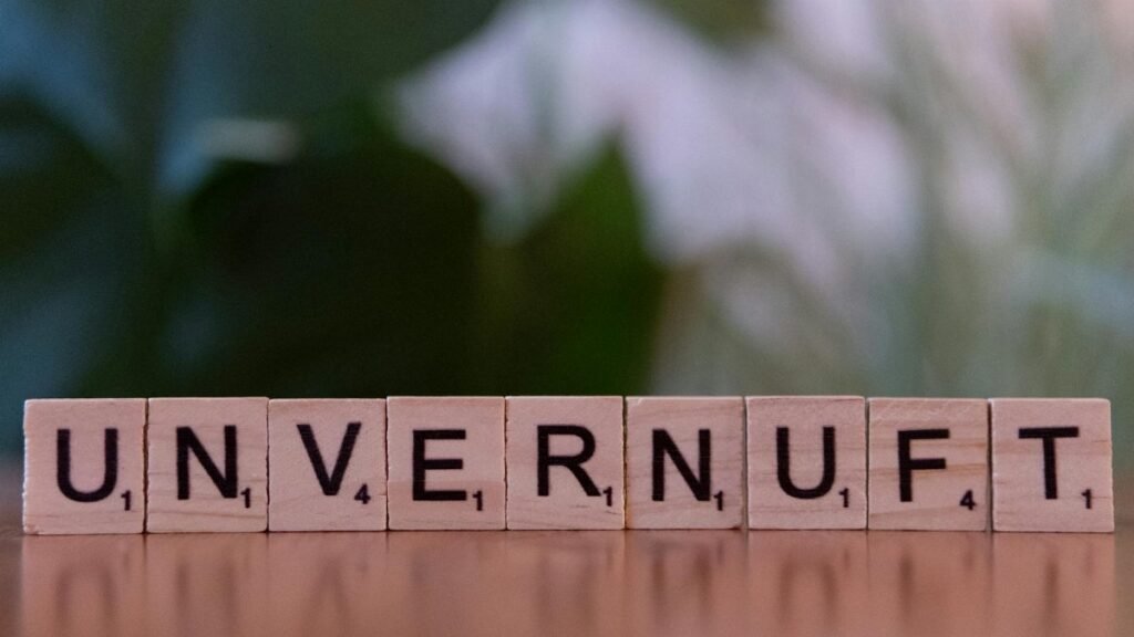 Close-up of wooden Scrabble tiles spelling 'UNVERNUFT' against a blurred background.