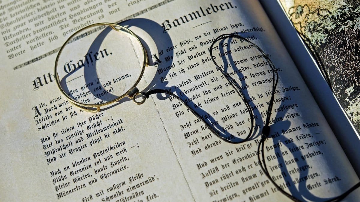 Close-up of vintage magnifying glass on open book, casting a shadow in sunlight.